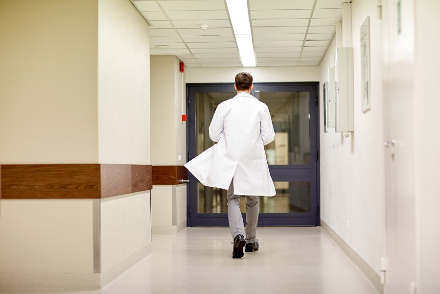 Sairaalan käytävällä lääkäri kävelemässä yksin poispäin takinliepeet heiluen.