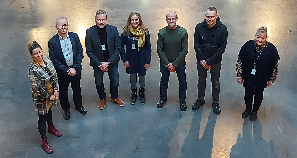 Ryhmä ihmisiä seisoo ja katsoo kameraan.