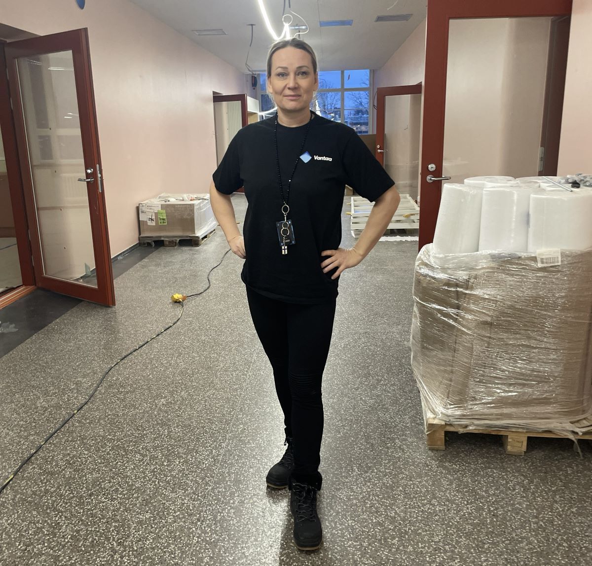 Vaalea nainen seisoo rakennuksne käytävällä.